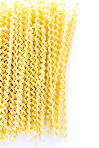 Organic yellow long pasta spirals on a white background.
