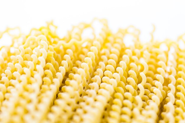 Organic yellow long pasta spirals on a white background.