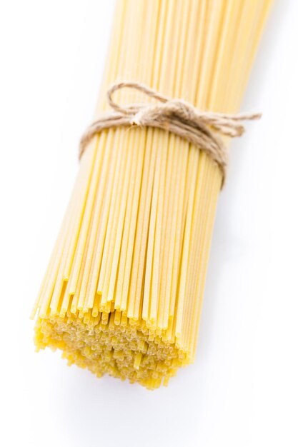 Organic yellow spaghetti pasta on a white background.