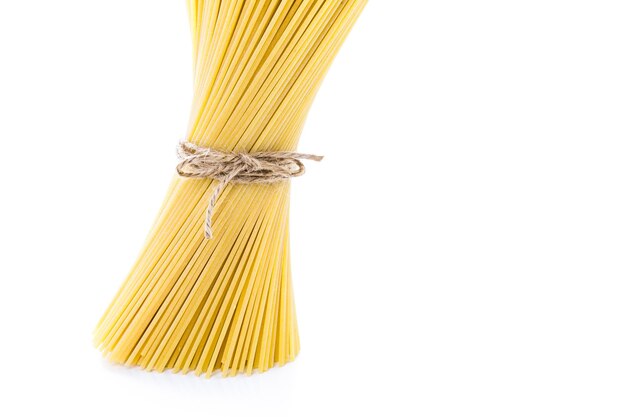 Organic yellow spaghetti pasta on a white background.