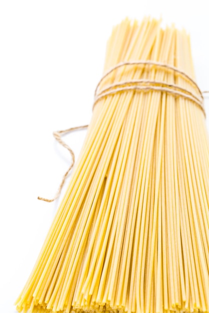 Foto pasta gialla organica degli spaghetti su un fondo bianco.