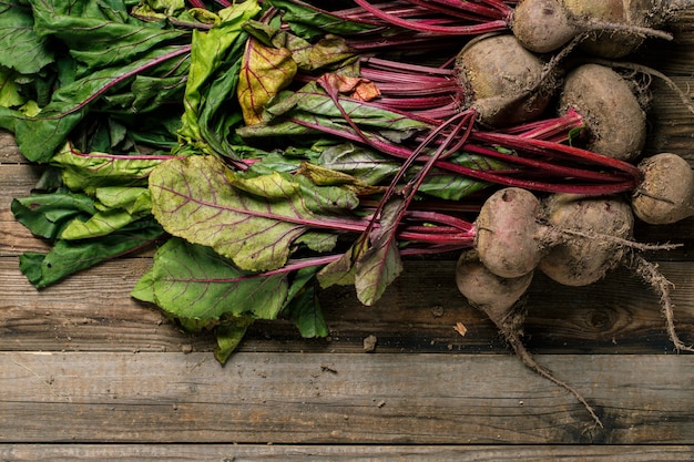 Organic young beets with green leaves on wooden table