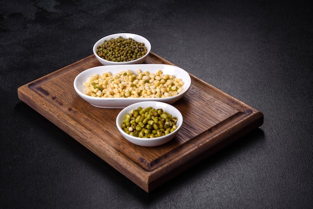 Organics fresh Baby Green Bean Sprouts in white ceramic bowl on a dark concrete background