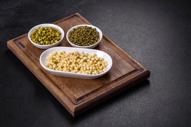 Organics fresh Baby Green Bean Sprouts in white ceramic bowl on a dark concrete background