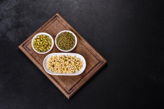 Organics fresh Baby Green Bean Sprouts in white ceramic bowl on a dark concrete background