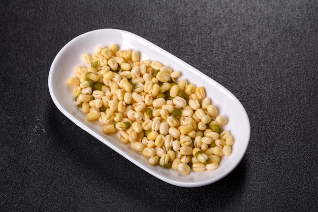 Organics fresh Baby Green Bean Sprouts in white ceramic bowl on a dark concrete background