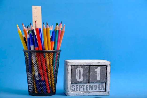 Organisator met potloden en liniaal briefpapierstandaard en houten kalender met datum 01 september blauwe achtergrond