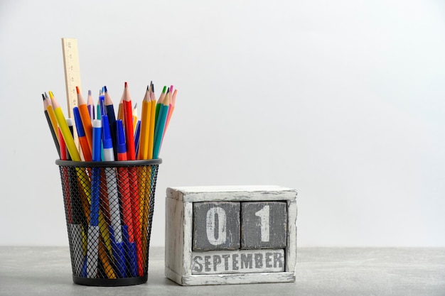 Organisator met potloden en liniaal, schrijfgereedschapsstand en houten kalender met datum 1 september