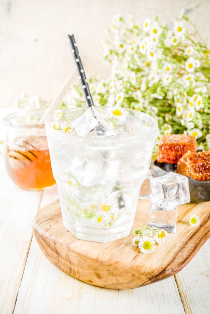 Organisch dieet detox zomer drank, doordrenkt water drinken met kamille en honing, op witte houten tafel, met kamille bloemen en honing in een pot. kopieer ruimte