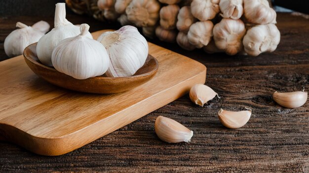 Organische rauwe knoflookbollen knoflookknoppen op houten snijplank, houten tafel en knoflooknoppen