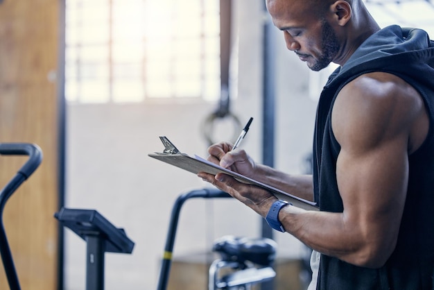 Photo organising and stocking supplies for all gym patrons. shot of a muscular young man writing notes on a clipboard while working in a gym.