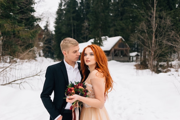 При организации свадьбы зимой жених и невеста нежно обнимают друг друга стоя на улице.