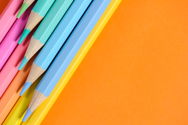 Organized colorful wooden pencils, isolated on the orange background. Copy space.