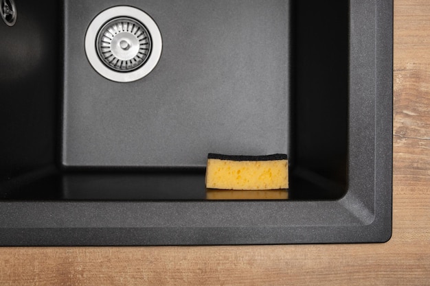 Organizer holder for a kitchen sponge in a black granite sink Storage and organization of space