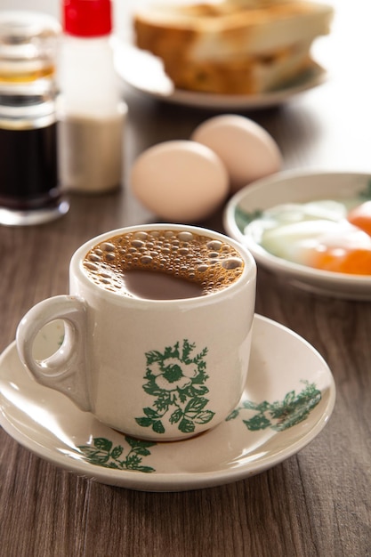 Восточный набор для завтрака в Малайзии, состоящий из тостового хлеба с кофе наси лемак и полувареного яйца.