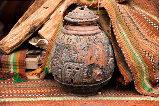 восточный керамический кувшин с орнаментом на рыночной площади стоит на тканых коричневых этнических коврах