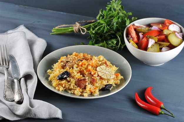 Oriental dish   plov with prunes, salad with onions and pickles, parsley