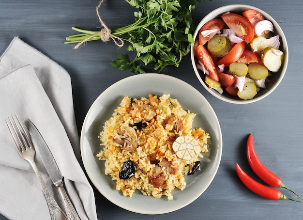 Foto piatto orientale plov con prugne secche, insalata con cipolle e sottaceti, prezzemolo