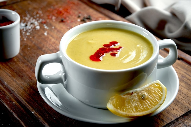 Photo oriental dish - a yellow lentil cream soup in white on a dark table piala