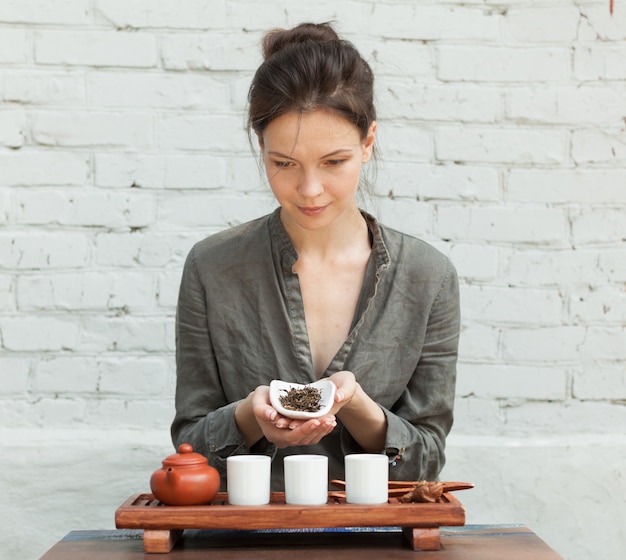 Oriental Master of tea ceremony with white brick wall on the background. 