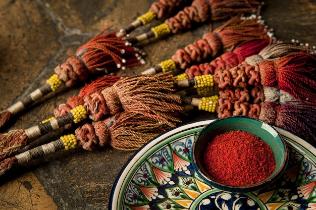 Oriental spices in cups and decorated adorned with a whip on an old worn paving stone. oriental spices and decorations on decorative old tiles