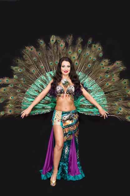 Oriental woman in luxurious peacock feather dress.Black background