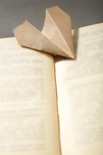 Origami airplane on old book close up