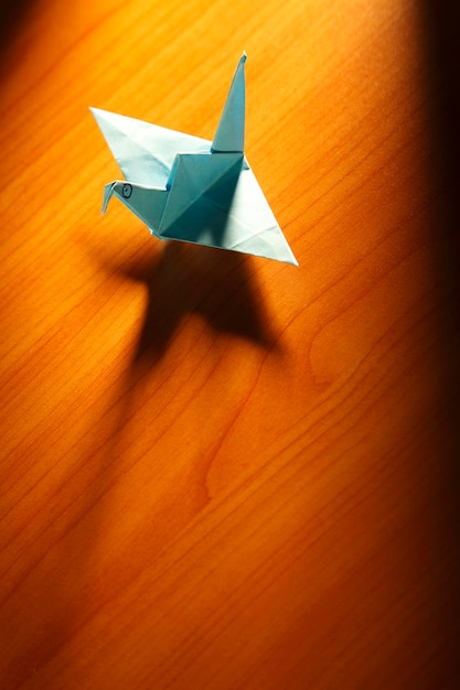 Origami bird crane on brown background