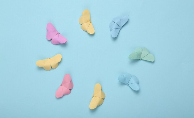 Origami butterflies flying in circle on blue background