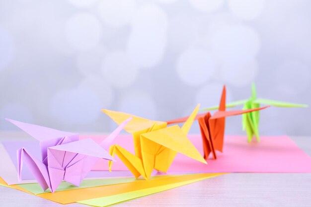 Origami cranes on wooden table on light background