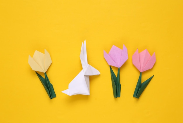 Origami easter bunny with tulips on yellow background Spring background