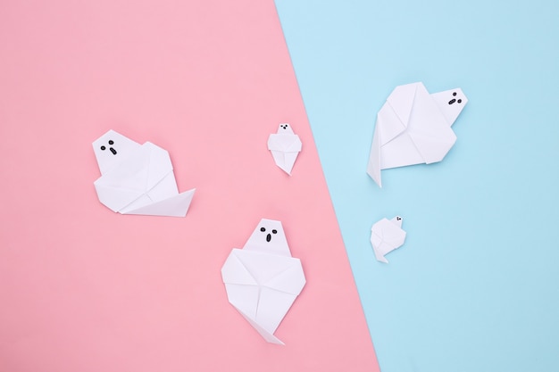 Origami ghosts on pink blue background. Handmade halloween decor. Top view