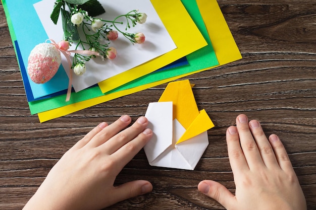 Istruzioni per l'origamiil bambino piega il pulcino di pasqua dell'origami fatto a mano