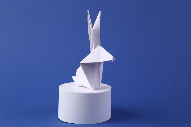 Origami konijn op het podium blauwe achtergrond minimalisme pasen concept