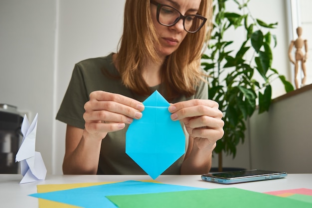 Origami lessons. Woman make origami easter rabbit from color paper