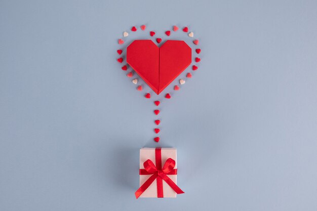 Origami paper heart balloon with gift box on blue table