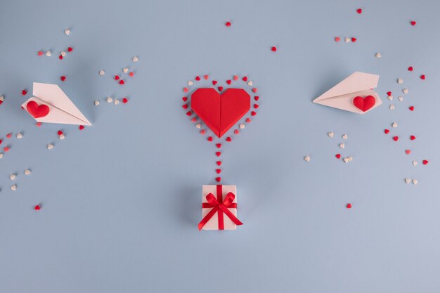 Origami paper heart balloon with gift box on blue table