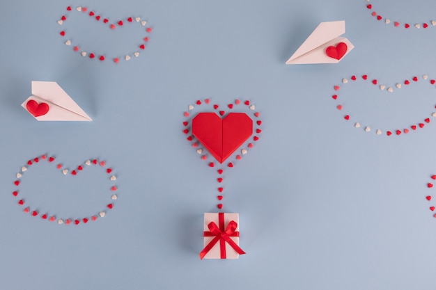 Origami paper heart balloon with gift box on blue table