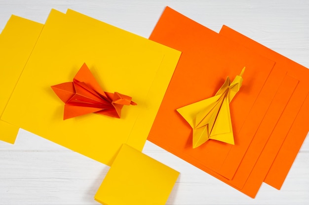 Origami Papier oranje en gele zwanen op een witte achtergrond Een vergadering Uitzicht van boven Creatie