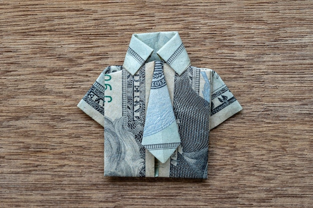 나무 배경에 달러 지폐로 만든 종이 접기 셔츠 근접 촬영 달러 지폐 Tshirt