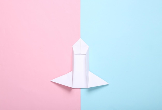 Origami space rocket shuttle on bluepink pastel background Minimalism Startup Top view