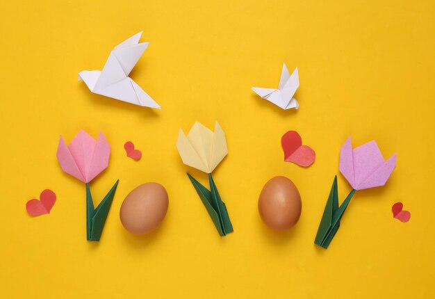 Origami tulips pigeons eggs and hearts on yellow background Spring easter background