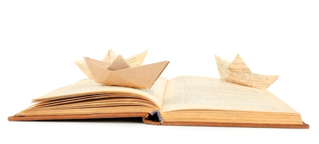 Origamiboot op oud boek dat op wit wordt geïsoleerd
