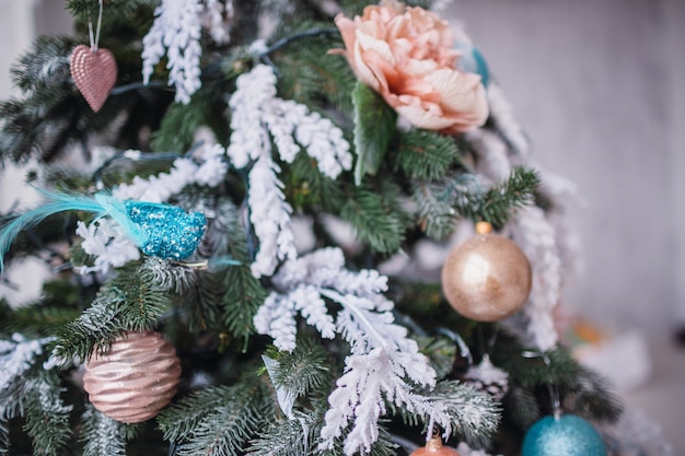 Original decor and toys hangs on rich Christmas tree standing in a cosy room