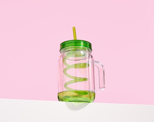 Фото Оригинальный пустой стакан для различных коктейлей и напитков с зеленой изогнутой соломинкой