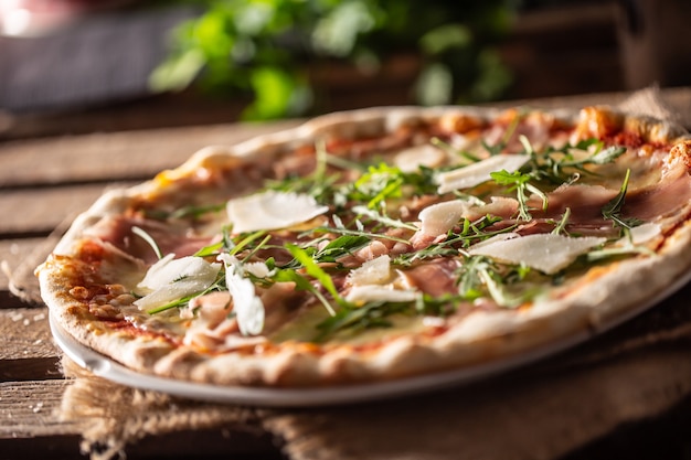 Original Italian pizza with prosciutto, parmesan cheese and rocket leaves.