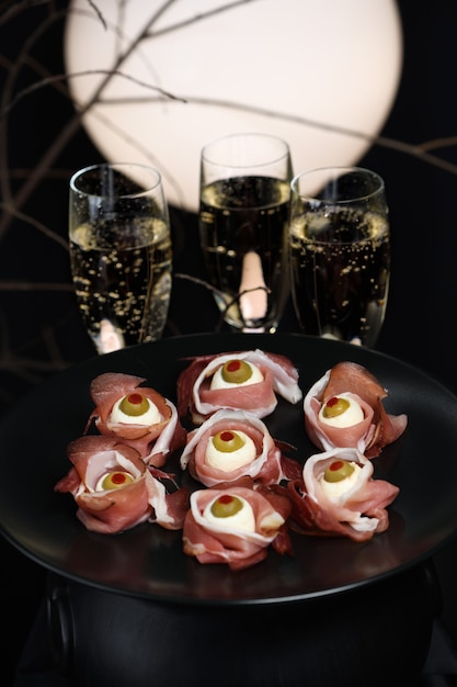 Originele halloween-snacks. oogbollen gekookt van ham met mozzarella, olijven gevuld met rode peper