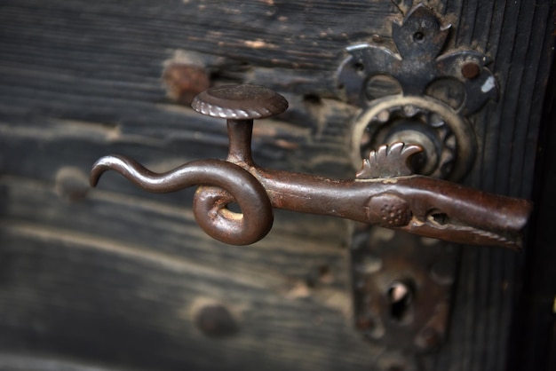 Ornamentele vintage ijzeren deurhandgreep op houten deur.