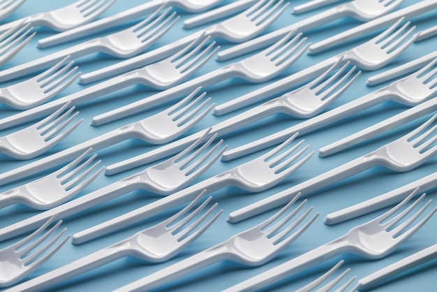 Ornorazovye white plastic forks on a blue background. Pattern, template, background, studio shot.