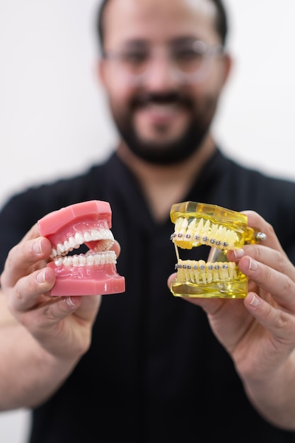 orthodontist met plastic menselijke kakenmodellen met metalen tandbeugels en transparante aligners